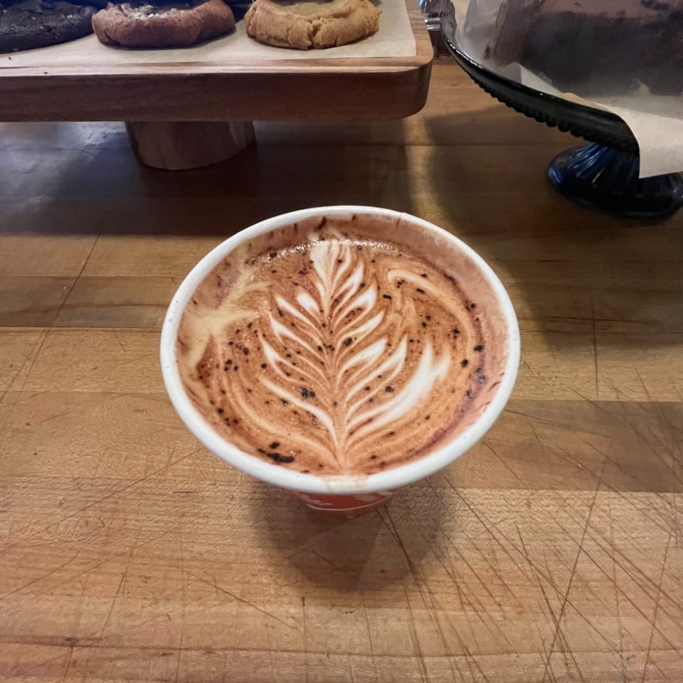 Latte with leaf-shaped latte art at the cafe counter.