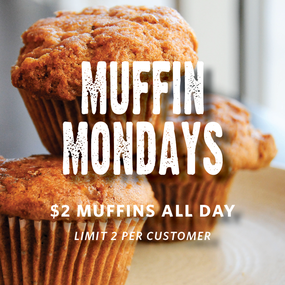 Close-up of golden-brown muffins with promotional text announcing $2 muffins all day, limited to two per customer.